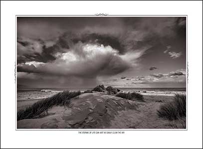 B&W sand dune and moving storm cloud om beach.